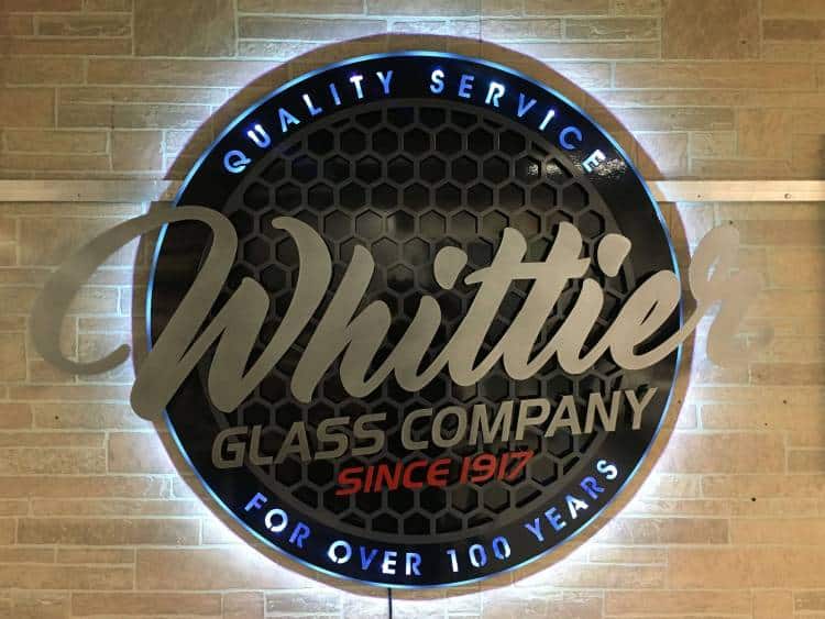 Whittier Glass Company round edge-lit sign over a honeycomb backer, Quality Service For Over 100 Years around the rim.