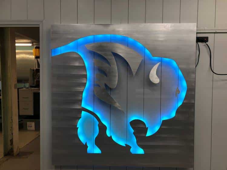 Air National Guard buffalo cut through a brushed aluminum panel, backlit blue.