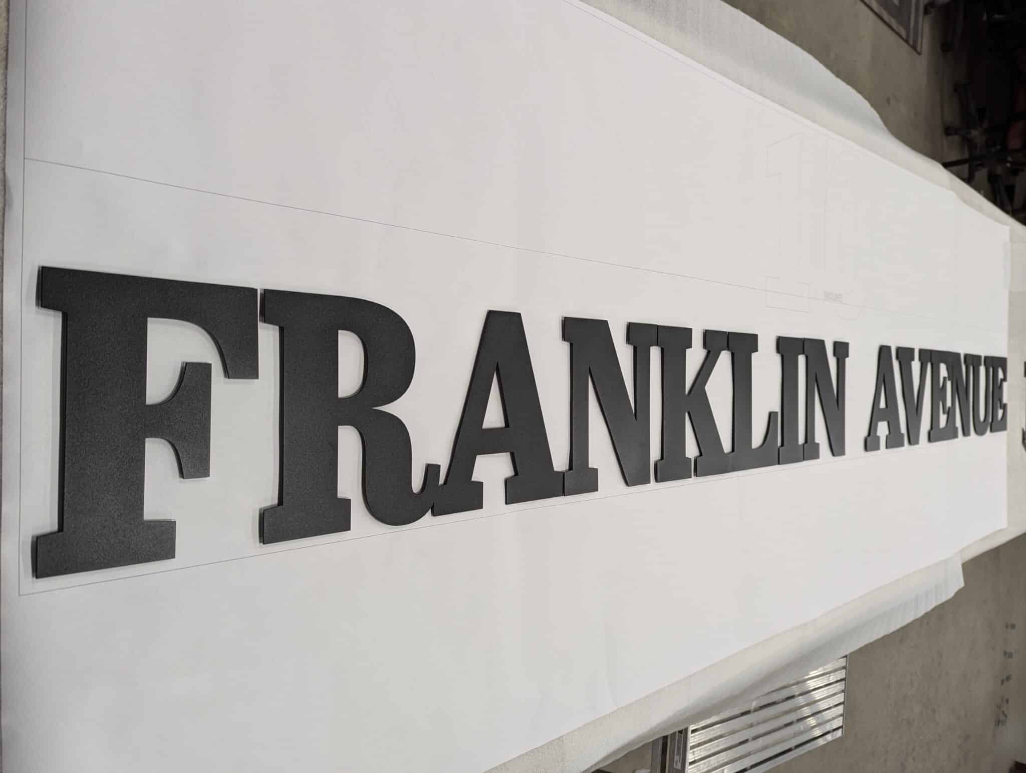 Custom metal building identification sign for 10 Franklin mounted on a modern architectural facade