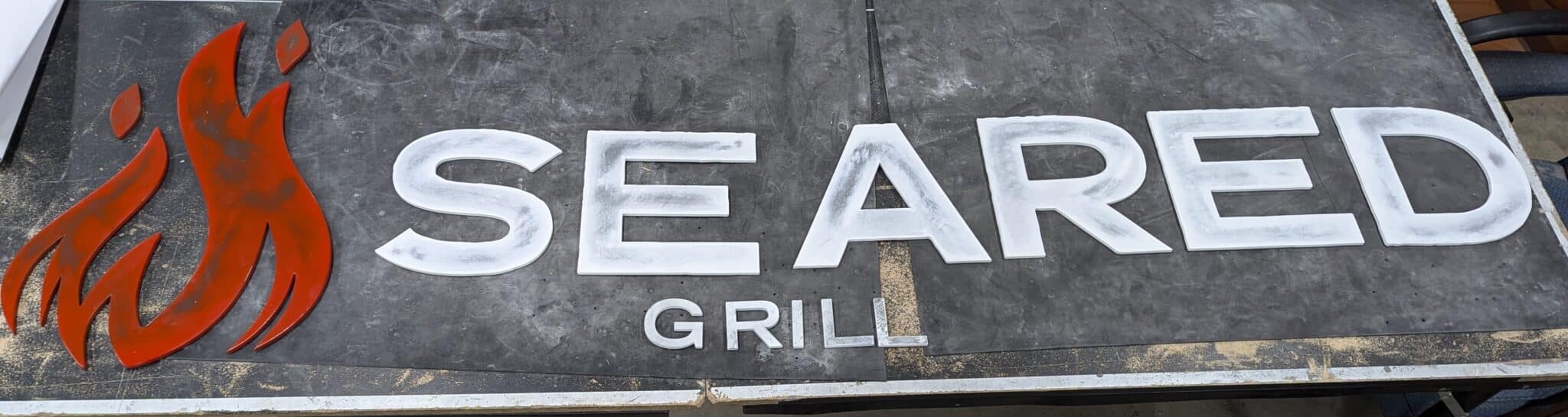 Custom dimensional metal logo sign for Seared Grill restaurant with bold lettering