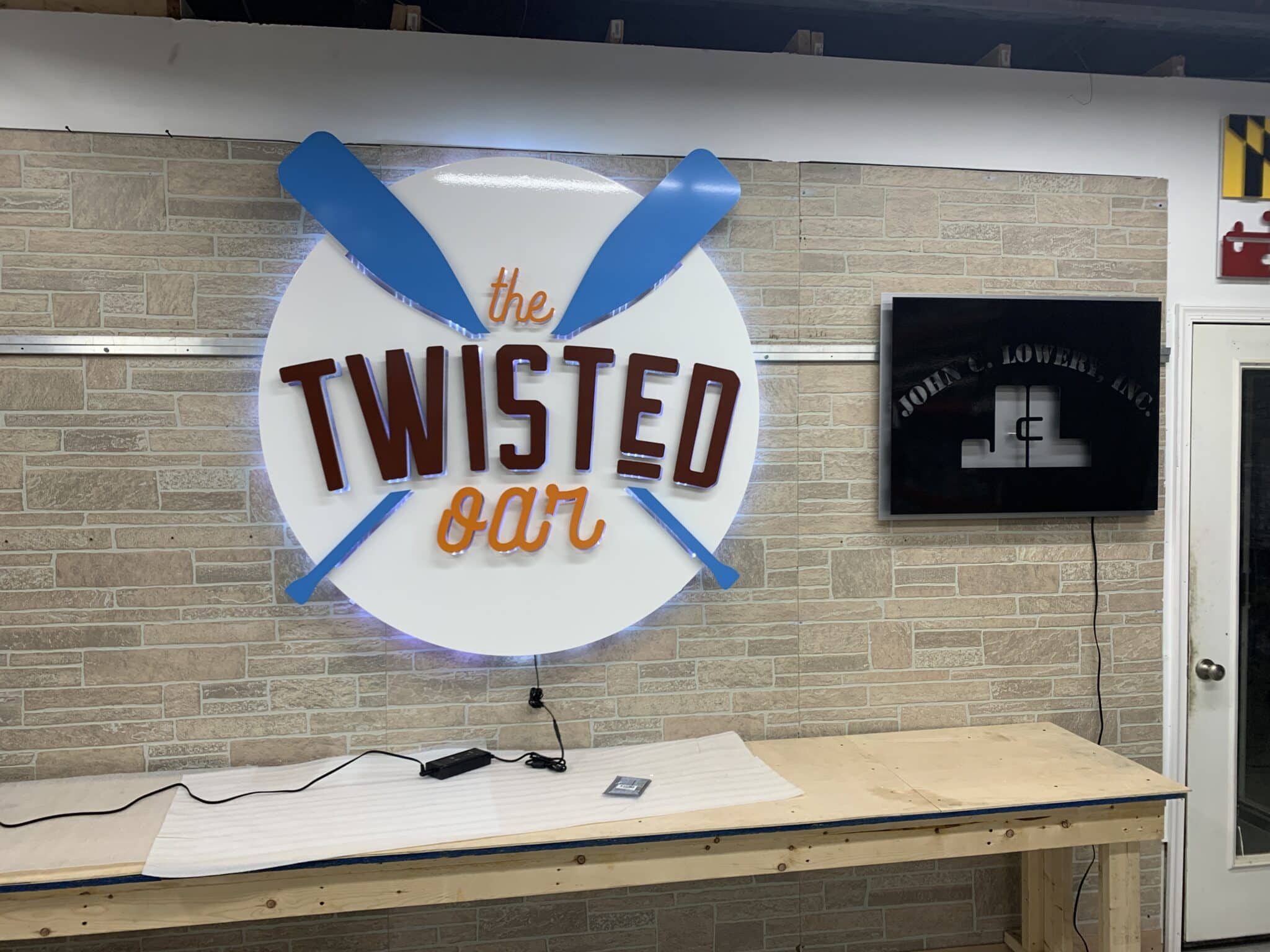 Illuminated dimensional metal logo sign at The Twisted Oar restaurant entrance