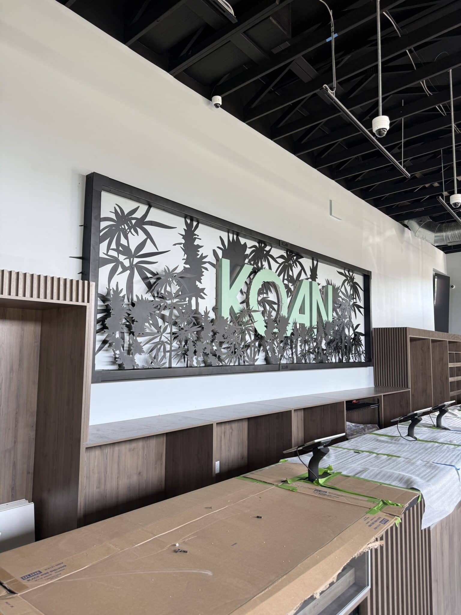 KOAN Cannabis dispensary signage, cut metal lettering on a feature wall above the counter