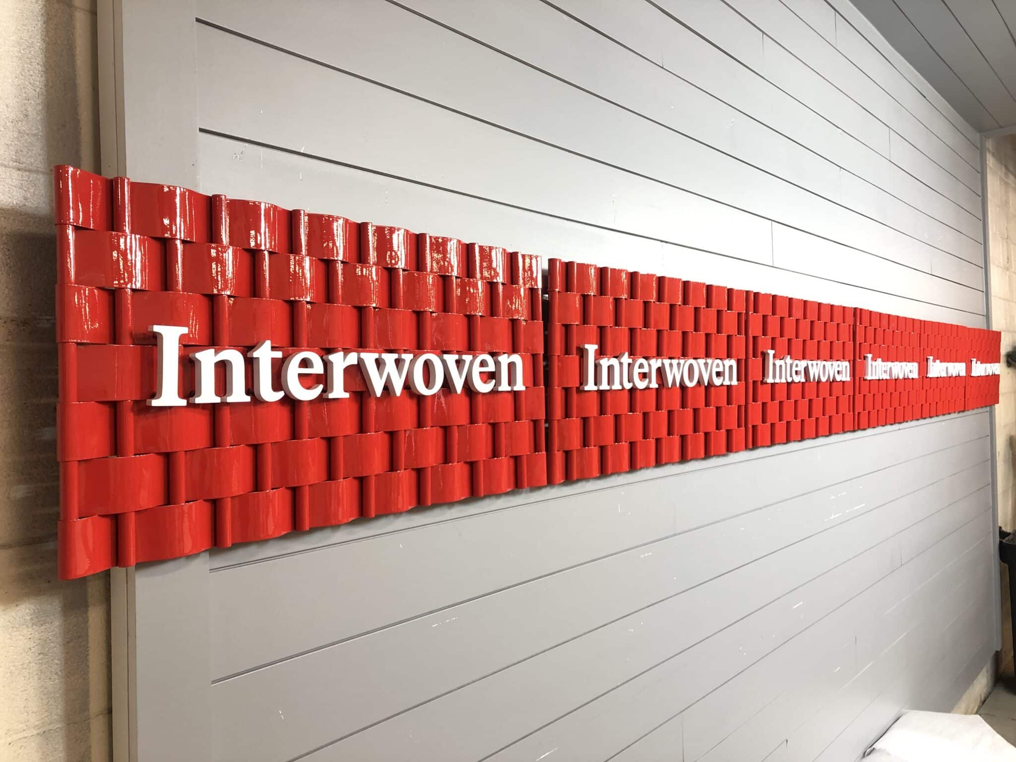Multiple finished Interwoven signs lined up showing the uniform red powder coat finish across the production batch