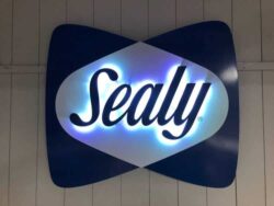 Sealy sign lit, white LEDs washing out from behind the script and the white lens.