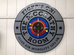 The McCarthy Room plaque for the 321st Air Mobility Ops Squadron, brushed gray with a red and blue compass emblem at its center.