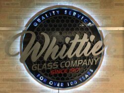 Whittier Glass Company round edge-lit sign over a honeycomb backer, Quality Service For Over 100 Years around the rim.