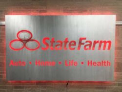 State Farm sign on a brushed panel, Auto Home Life Health beneath the name, glowing red.
