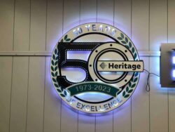 Heritage Mechanical 50 Years of Excellence badge with a laurel wreath, halo-lit LED and glowing blue.