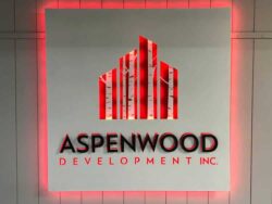 Aspenwood Development sign with a red city skyline above raised lettering, framed by a red LED halo.