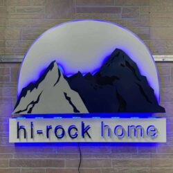Hi-Rock Home sign with layered mountains against a pale sky, the name lit blue on a bar beneath.
