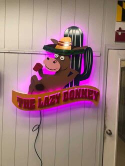 The Lazy Donkey sign with a cartoon donkey in a sombrero beside a cactus, glowing magenta.