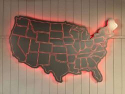 Autos Drive America sign cut as an outline map of the United States with state borders, backed by a red LED halo.