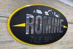 Romine Tile Service sign from an angle, the yellow arrow running out to the edge of the oval.