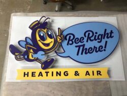 Bee Right There Heating and Air sign laid flat in the shop, the layered bee and speech bubble finished before install.