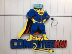 DMV Computerman sign shaped as a caped superhero with a monitor for a head, above bold lettering.
