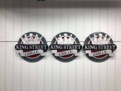 Three smaller King Street Grille signs finished in the shop, crowns above the ribbon lettering.