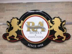 RA Homes & Associates sign with two gold lions flanking the monogram, Since 1998 on the lower banner.