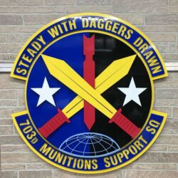 703d Munitions Support Squadron seal, crossed swords and a missile between two stars over a globe.