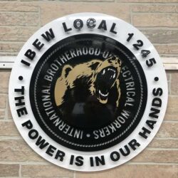 IBEW Local 1245 seal with a snarling bear at its center, The Power Is In Our Hands around the rim.