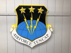 Air Force TENCAP shield sign with three stars over lightning bolts and a globe, above a name scroll.