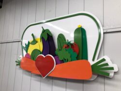 Merrie's Market wall piece built from layered vegetables around a red heart, inside a green outline.