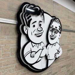 Wall piece of two cartoon men in black and white, one with folded arms and one in glasses, mounted on stone.