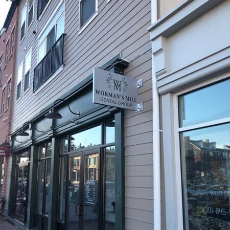The Worman's Mill Dental Group blade sign installed, projecting from the storefront above the windows.