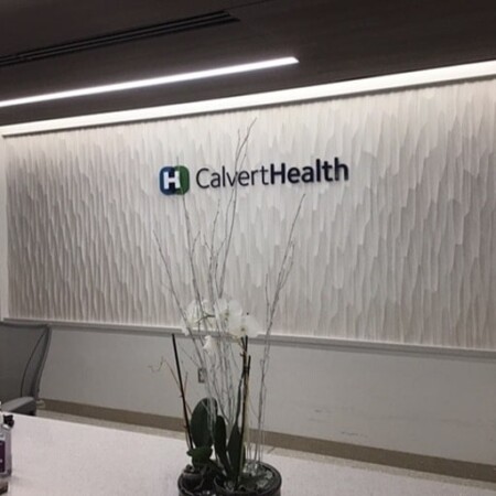 CalvertHealth dimensional letter sign on the textured lobby wall behind the reception desk.