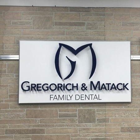 Gregorich & Matack Family Dental panel sign in white, a navy GM monogram above the name.