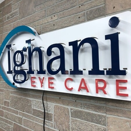 Ighani Eye Care panel sign in white with navy lettering, a teal swoosh and red Eye Care beneath.