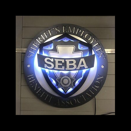 Sheriff's Employees' Benefit Association seal lit, blue light spilling through the ring lettering.