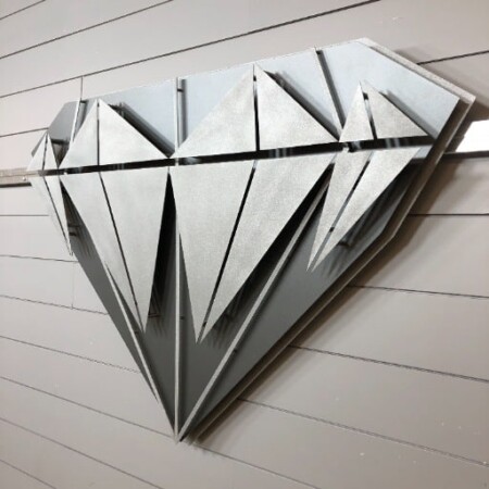 Diamond Equity Investments sign cut as a faceted diamond in brushed aluminum, every facet a separate layer.