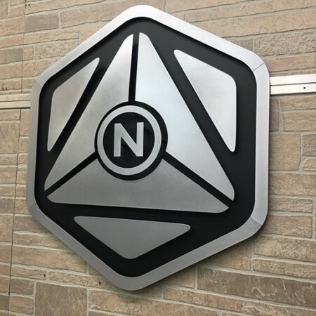 NeuroScouting hexagonal sign in brushed and black aluminum, an N inside a faceted shield.