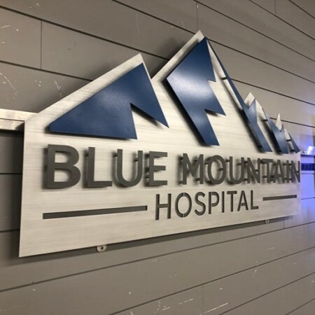 Blue Mountain Hospital sign with navy mountain peaks above dimensional lettering on a brushed panel.