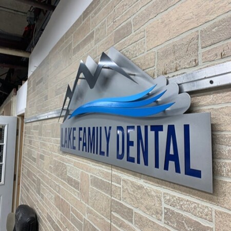 Lake Family Dental sign from a sharp angle, the layered peaks and wave standing off the stone.