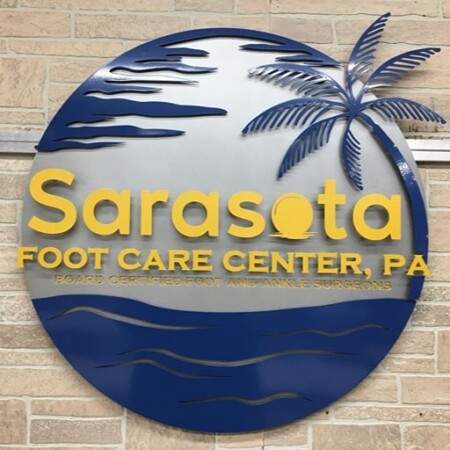 Sarasota Foot Care Center sign from an angle, the cut palm fronds standing clear of the brushed face.