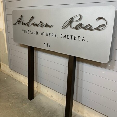 Layered brushed aluminum post-mounted sign for Auburn Road Vineyards in brushed silver and dark bronze/black posts.
