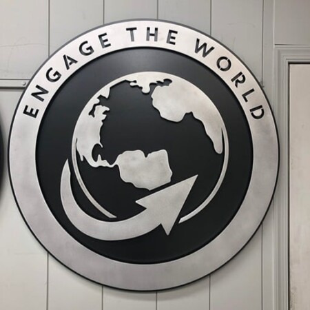 Northwood Baptist Church round sign reading Engage the World, a globe and arrow cut in brushed steel.