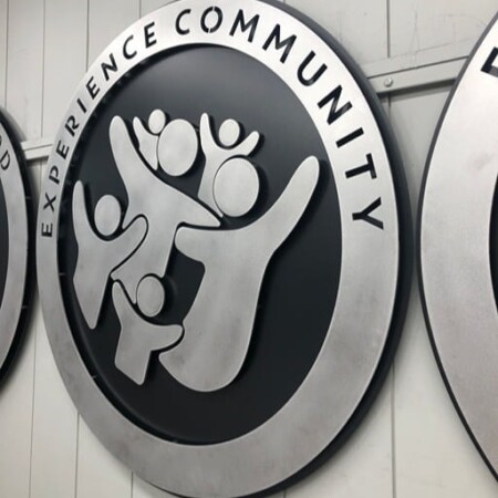Northwood Baptist Church round sign reading Experience Community, raised figures with arms lifted.