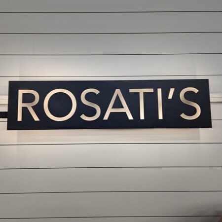 Rosati's sign in black with raised brushed lettering, mounted on white siding.