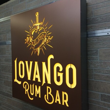 Lovango Rum Bar face-lit LED sign angled against the wall, the gold letters and emblem raised off the brown face.