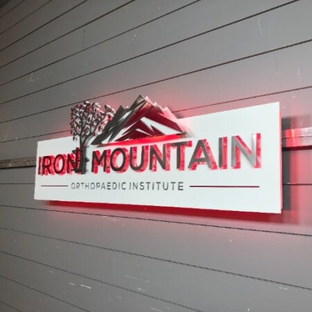 Iron Mountain Orthopaedic Institute panel sign with a red peak and pine above the name, glowing red.