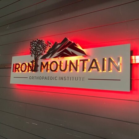 Iron Mountain Orthopaedic sign with the red LED halo at full strength, washing the wall behind the panel.