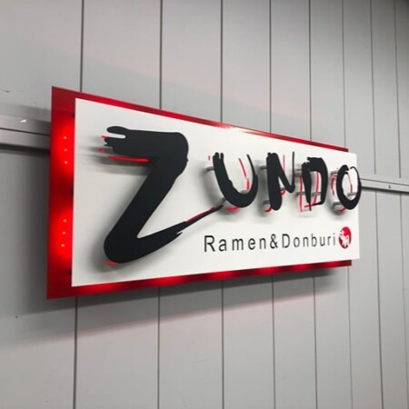 Zundo Ramen & Donburi sign from an angle, the brushstroke letters standing off the red-edged panel.
