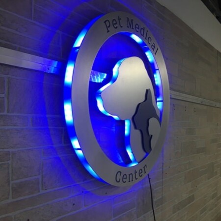 Pet Medical Center of Pasco sign angled sharply, the blue LEDs visible inside the open ring.