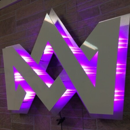 Coronation Media crown monogram in brushed aluminum, halo-lit LED and glowing purple on brick.