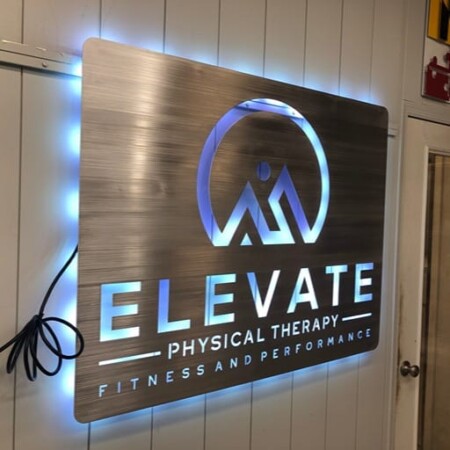 Elevate Physical Therapy panel sign in brushed aluminum with a mountain logo, halo-lit LED and glowing blue.
