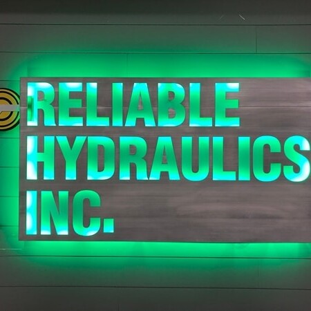 Reliable Hydraulics Inc. sign lit, the same letters reading clearly against a green LED halo.