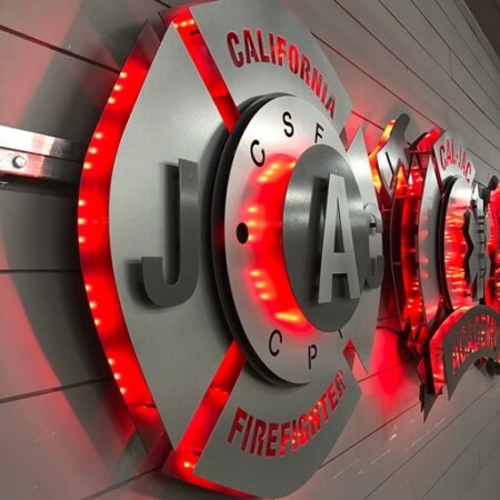 California JAC Firefighter badges lined up along the wall, red LEDs raking away down the row.