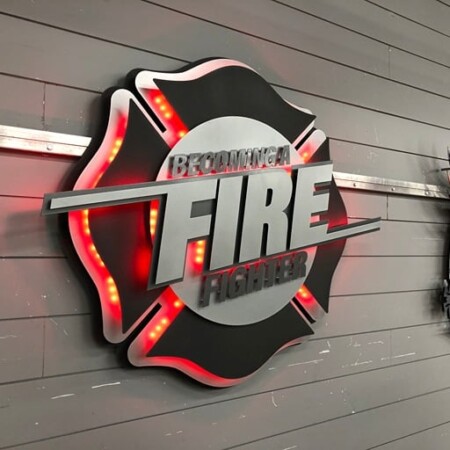 Becoming a Fire Fighter badge from an angle, the red LEDs visible around the edge of the cross.